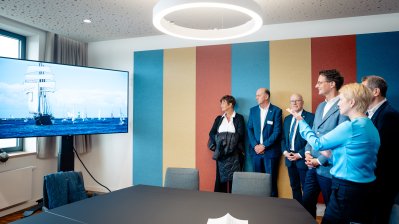 Die Anwesenden schauen auf einen Monitor mit Segelschiffen