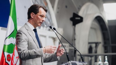 MP Wüst während seiner Rede vor einer Raumfahrtkapsel