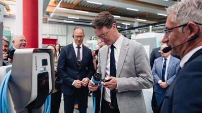 Ministerpräsident Wüst steht an einer Zapfsäule im Gespräch mit einem Mitarbeiter