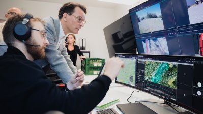 Ministerpräsident Wüst und ein Mitarbeiter schauen auf mehrere Monitore