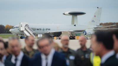 Mneschen unscharf im Vordergrund, im Hintergrund ein NATO-Flugzeug auf der NATO-Air Base Geilenkirchen