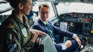 Ministerpräsident Hendrik Wüst sitzt in einem Flugzeug und spricht mit einer Pilotin