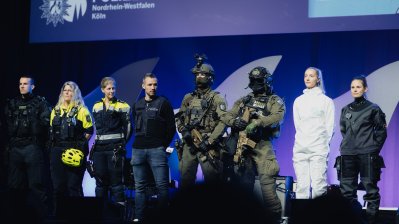 Polizistinnen und Polizisten in verschiedener Einsatzkleidung stehen auf der Bühne
