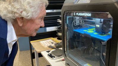 ein Mann beugt sich zu einer Maschine mit Sichtfenster ins Innere