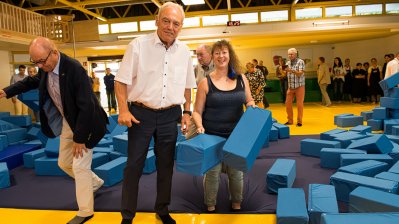 Staatssekretärin Milz mit dem Präsidenten des Landessportbundes NRW, Herrn Walter Schneeloch, an einer Schnitzelgrube gefüllt mit großen, blauen, gepolsterten Quadern.