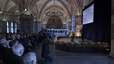 Bundespräsident Steinmeier hält eine Rede auf einer Bühne mit Rednerpult stehend.