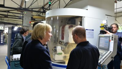 Ministerpräsidentin Kraft spricht mit einem Arbeiter vor einer großen Maschine