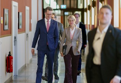 Ministerpräsident Hendrik Wüst und Ministerin Feller gehen auf einem Flur zur Pressekonferenz