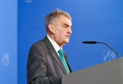 Minister Reul spricht an einem Rednerpult vor Flaggen