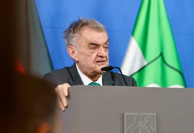 Minister Reul spricht an einem Rednerpult vor Flaggen