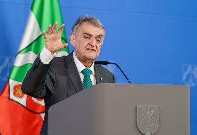 Minister Reul spricht an einem Rednerpult vor Flaggen