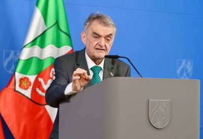 Minister Reul spricht an einem Rednerpult vor Flaggen