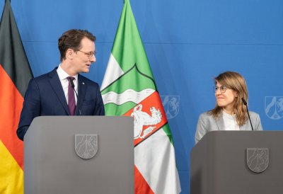 MP Wüst und Ministerin Schäffer stehen hinter ihren Rednerpulten und schauen sich an