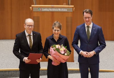 Ministerin Schäffer hält im Plenarsaal einen Blumenstrauß in der Hand, neben ihr der Landtagspräsident und der Ministerpräsident