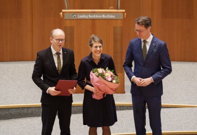 Ministerin Schäffer hält im Plenarsaal einen Blumenstrauß in der Hand, neben ihr der Landtagspräsident und der Ministerpräsident