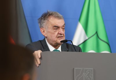 Minister Reul spricht an einem Rednerpult vor Flaggen