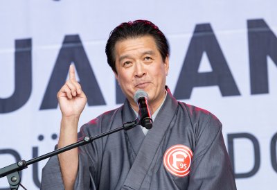 Ein Mann in traditionell japanischer Kleidung hält auf der Bühne einer Ansprache