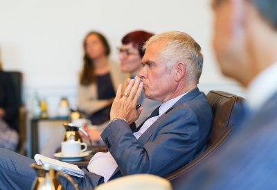Besprechungssituation in einem festlichen Raum, der Doyen hört gespannt zu