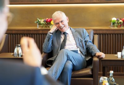 Besprechungssituation in einem festlichen Raum, der Doyen lacht