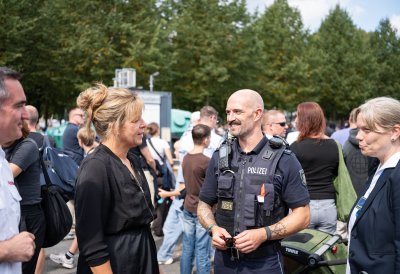 Wirtschaftsministerin Mona Neubaur unterhält sich mit einem Polizeibeamten
