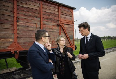 MP Wüst und die Antisemitismusbeauftragte Sylvia Löhrmann stehen mit dem Leiter der Führung vor einen Zugwagon