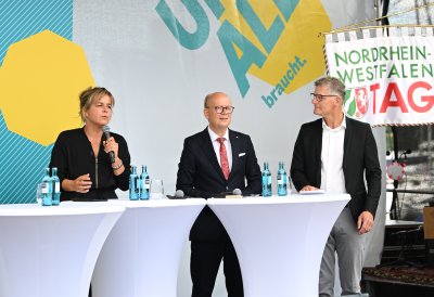 Landtagspräsident Kuper, die stellvertrende Ministerpräsidentin Neubaur und Oberbürgermeister Tilman Fuchs bei der Eröffnung auf einer Bühne