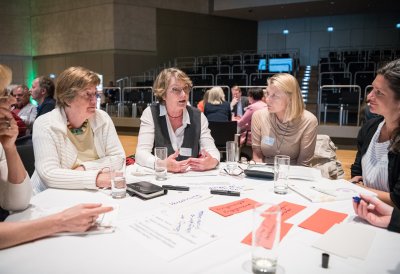 Mehrere Damen im Gespräch an einem runden Tisch sitzend.
