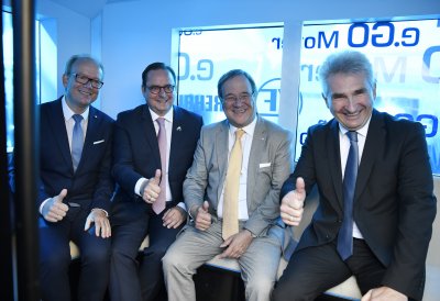 Die PErsonen sitzen auf einer Sitzbank im Bus und halten die Daumen hoch