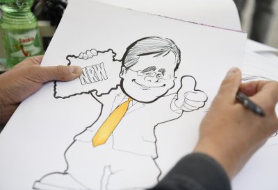 Ein Karikaturist zeichnet Ministerpräsident Armin Laschet mit gelber Krawatte und gehobenem Daumen
