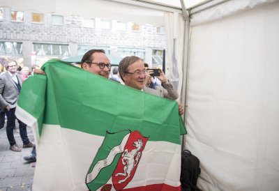 OB Kufen und Ministerpräsident Laschet halten eine NRW-Flagge in die Kamera