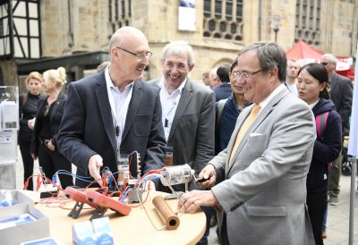 Ministerpräsident Armin Laschet steht an einem Stand mit elektronischen Gerätschaften