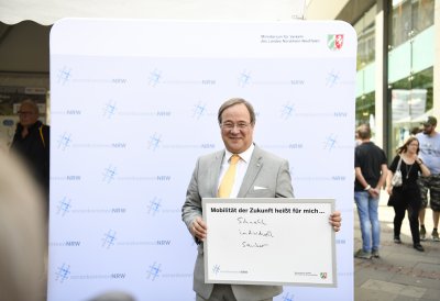 Ministerpräsident Laschet hält ein ausgefülltes Schild in die Kamera: Mobilität heißt für mich... "schnell, individuell, sauber"