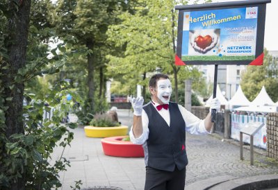 Ein Pantomimen-Darsteller mit einem Schild des Netzwerks Organspende