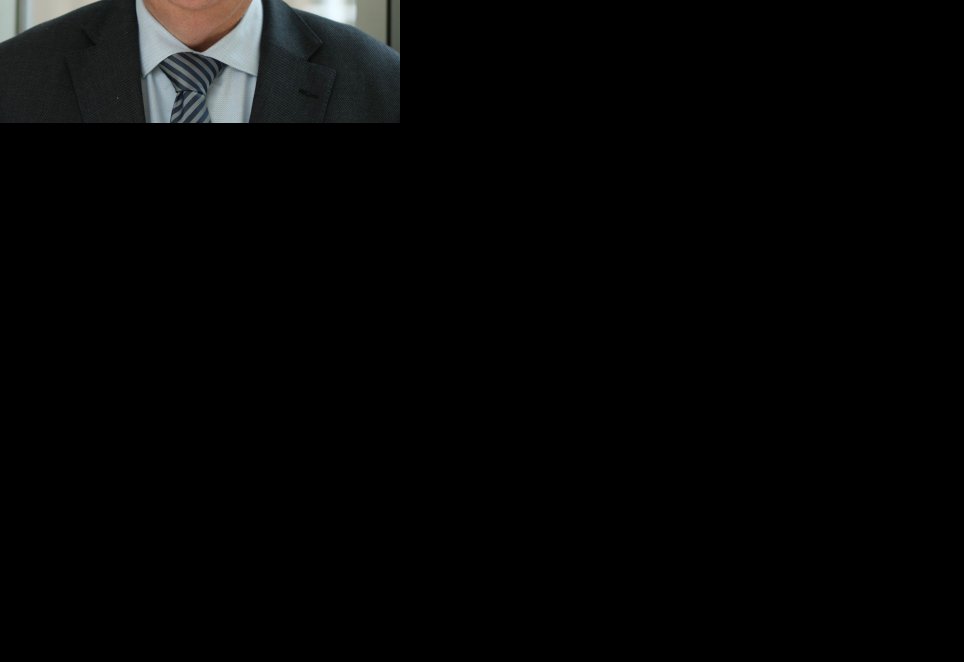 Klaus Georg Müller im Profil (Oberkörper) mit schwarzem Anzug, hellblauem Hemd und blau-schwarz gestreifter Krawatte, grauen Haaren und Brille.