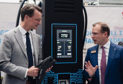 Ministerpräsident Wüst steht an einer Zapfsäule im Gespräch mit einem Mitarbeiter