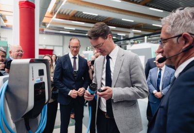 Ministerpräsident Wüst steht an einer Zapfsäule im Gespräch mit einem Mitarbeiter