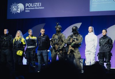Polizistinnen und Polizisten in verschiedener Einsatzkleidung stehen auf der Bühne