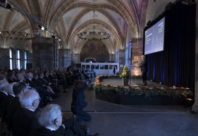 Bundespräsident Steinmeier hält eine Rede auf einer Bühne mit Rednerpult stehend.