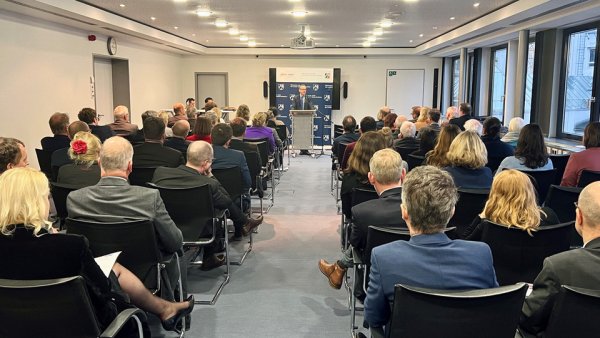 Das Publikum hört einem Redner am Rednerpult zu