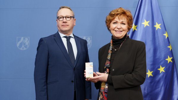 Justizminister Limbach und die Opferbeauftragte Havliza halten eine Packung K.O.-Tropfen-Schutz-Armband in die Kamera