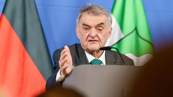 Minister Reul spricht an einem Rednerpult vor Flaggen