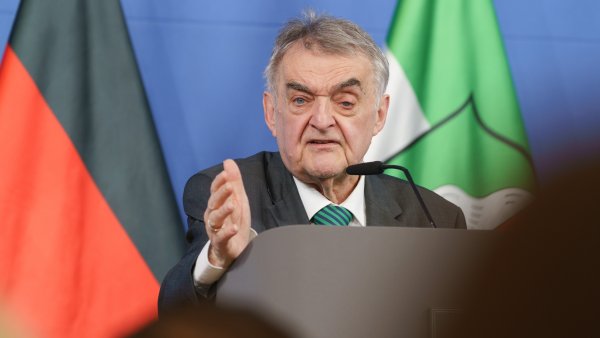 Minister Reul spricht an einem Rednerpult vor Flaggen