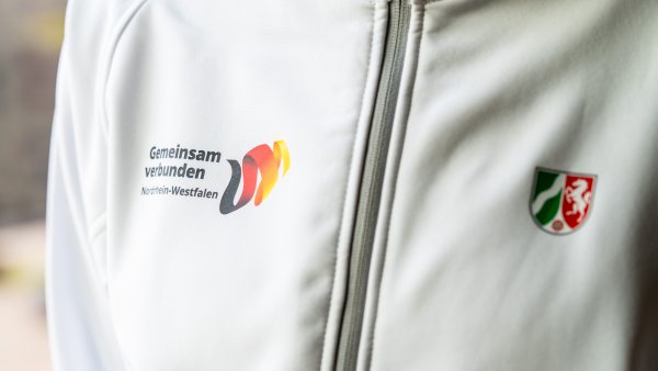 Ein Close-Up einer weißen Sportjacke mit dem NRW-Wappen und dem Logo von Gemeinsam verbunden