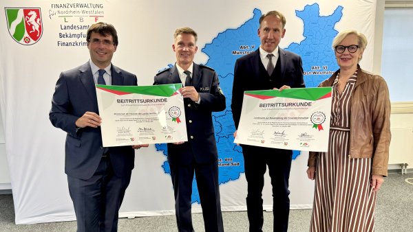 Minister der Finanzen Dr. Marcus Optendrenk, Netzwerkkoordinator Andre Niewöhner, Oberfinanzpräsident Reinhard Derix und LBF-Leiterin Stephanie Thien (v.l.) stehen vor einem Banner des Landeamtes zur Bekämpfung von Finanzkriminalität, in blau zu sehen eine Karte von NRW