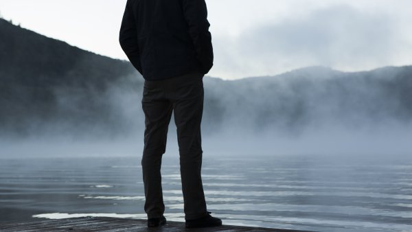 Ein Mann steht am See im Nebel