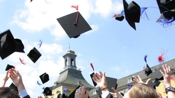 Das Foto zeigt Studierende, die im Rahmen ihres Studienabschlusses bei der Feier ihre Hüte in die Luft werfen.