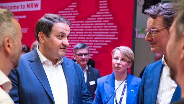 Minister Liminski und MP Wüst im Gespräch vor einer roten NRW-Fotowand auf dem Messegelände der gamescom