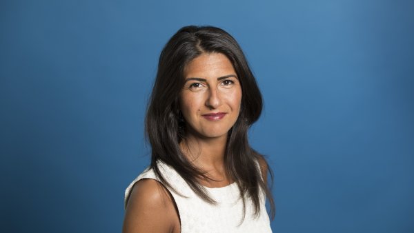 Staatssekretärin Serap Güler freundlich lächelnd - Hintergrund blau.