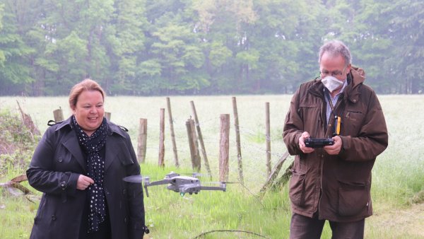 Ministerin Heinen-Esser steht in einer Wald-Lichtung vor einer fliegenden Drohne