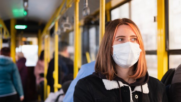 Eine junge Frau trägt eine Mund-Nasen-Schutz-Maske im Bus